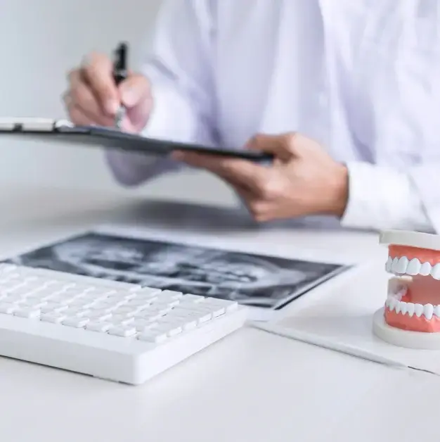 Dentist reviewing X-ray and dental model while taking notes on insurance and financing options.